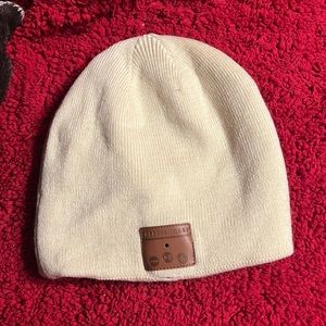 Off-white beanie winter hat with built in Bluetooth headphones w/ charging cord